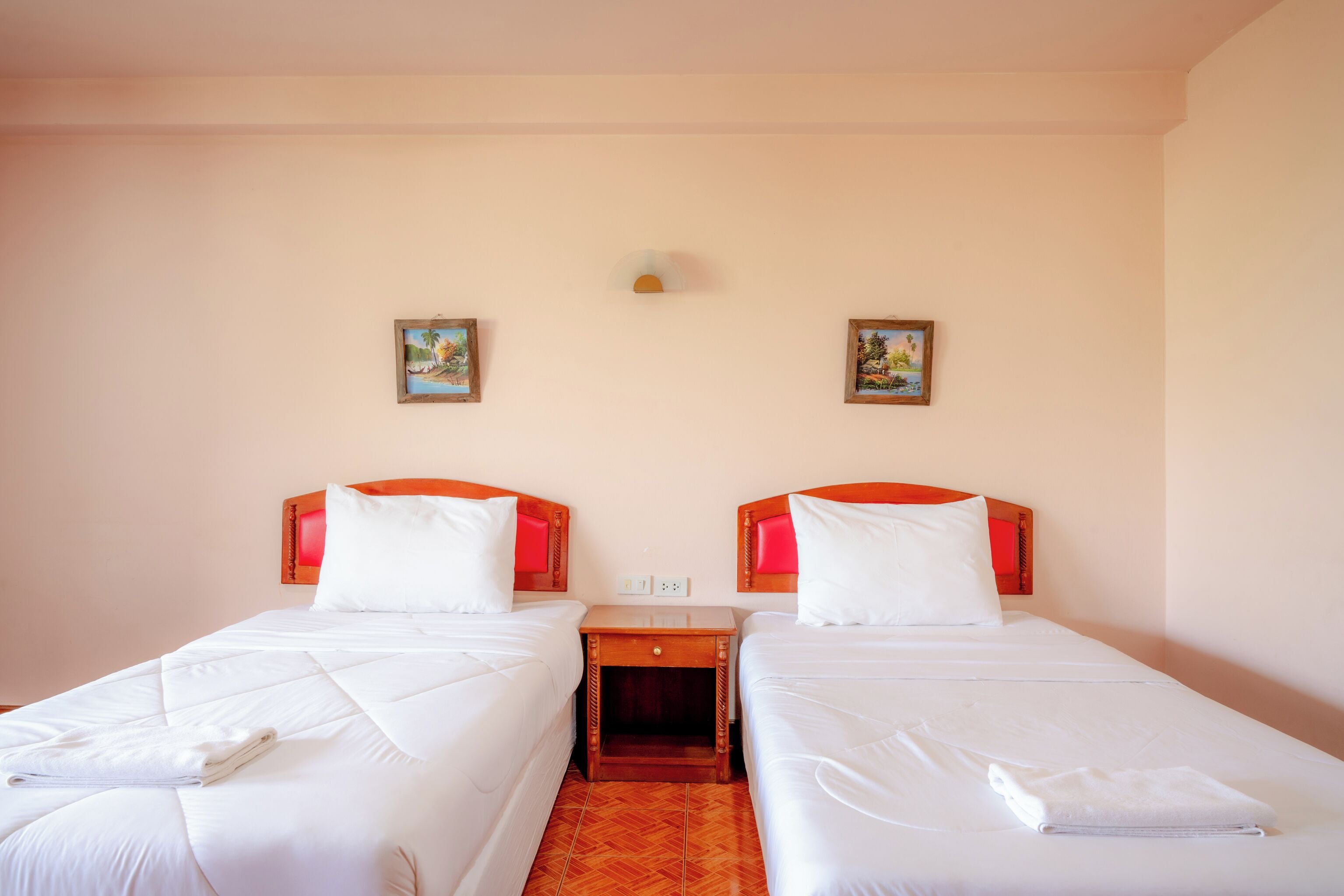 Una habitación de hotel con dos camas individuales, una mesita de noche de madera y una pequeña mesa.