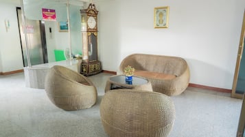 A lobby with wicker furniture, a clock, and a framed picture on the wall.