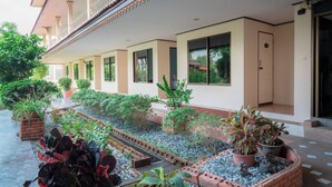 A hotel corridor with a tiled floor, potted plants, and a small water feature. - Kohloy Golden Park (Tak)