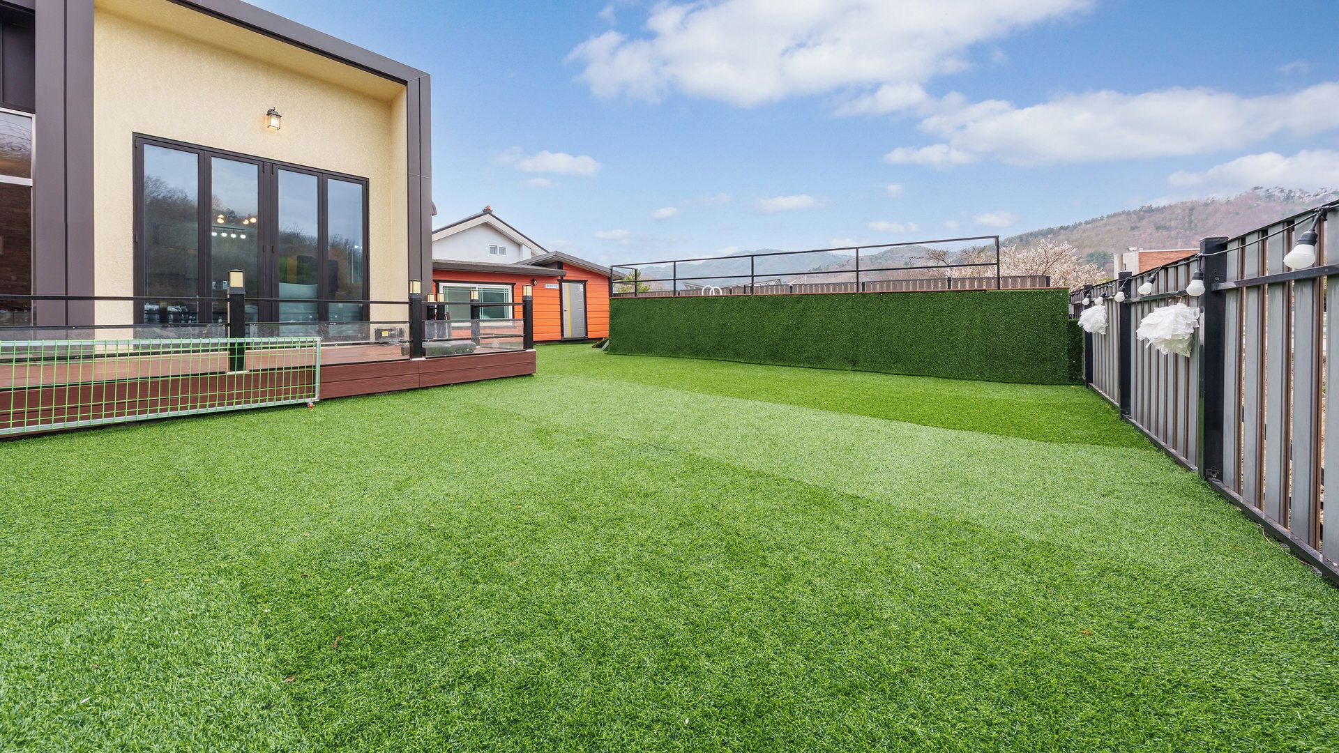 A modern building with a flat roof, large windows, and a well-maintained lawn.