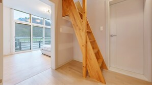 Un interno moderno con una scala in legno che conduce a un balcone.