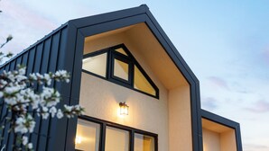 Un edificio moderno con tetto a due falde, ampie finestre e un lampadario sulla facciata.
