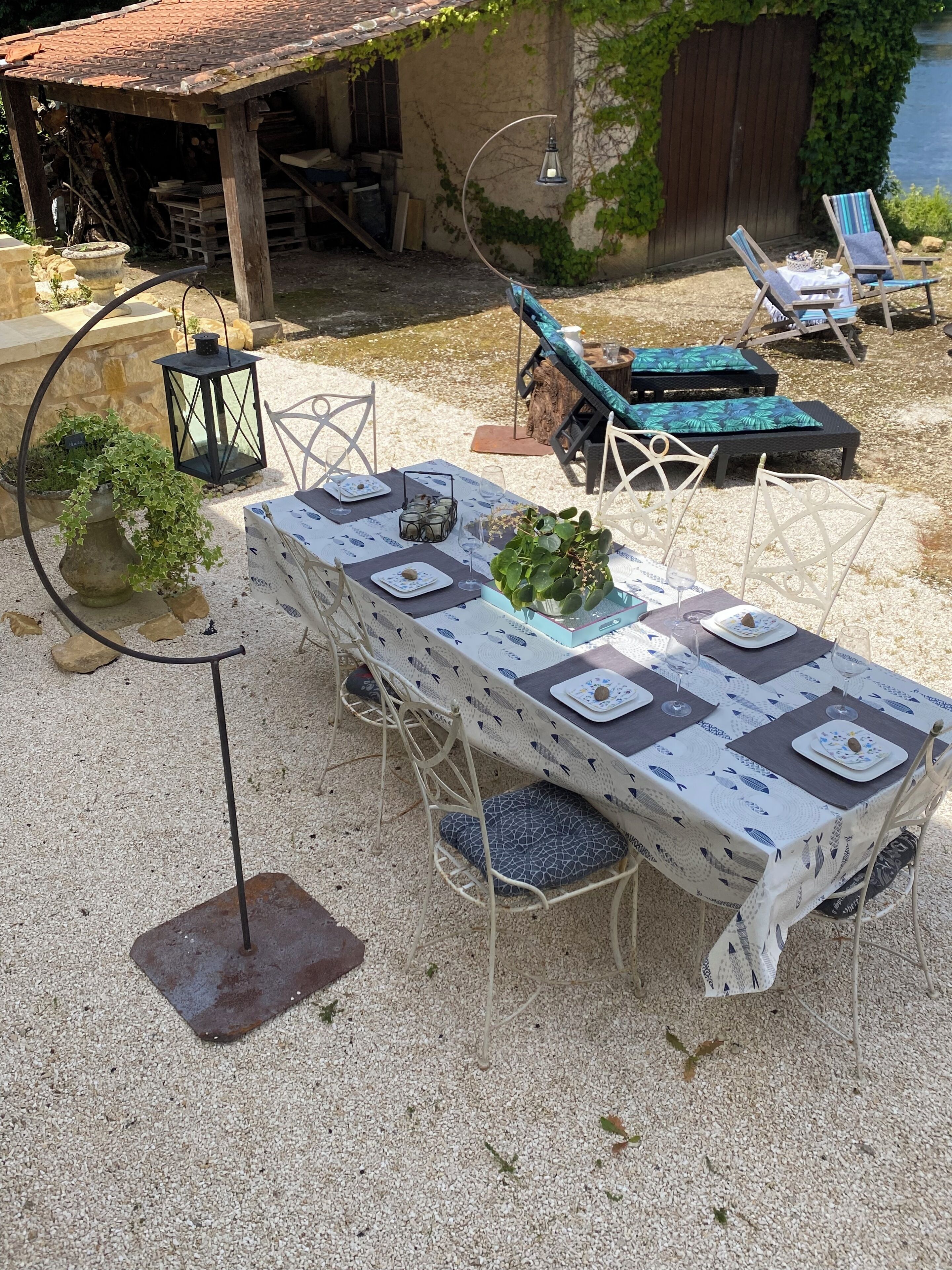 An outdoor dining area with a long table set for four, surrounded by chairs.