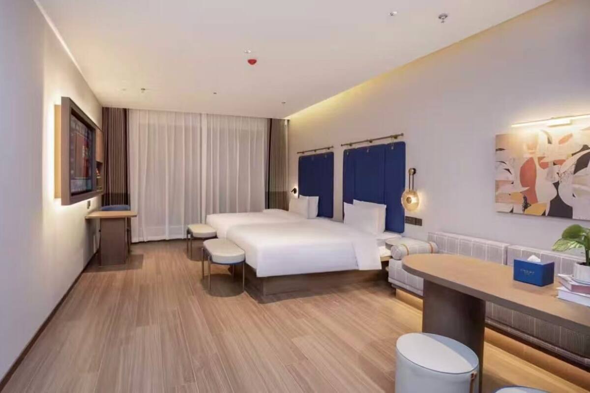 Una habitación de hotel moderna con una cama grande, mesitas de noche, un escritorio y una silla.