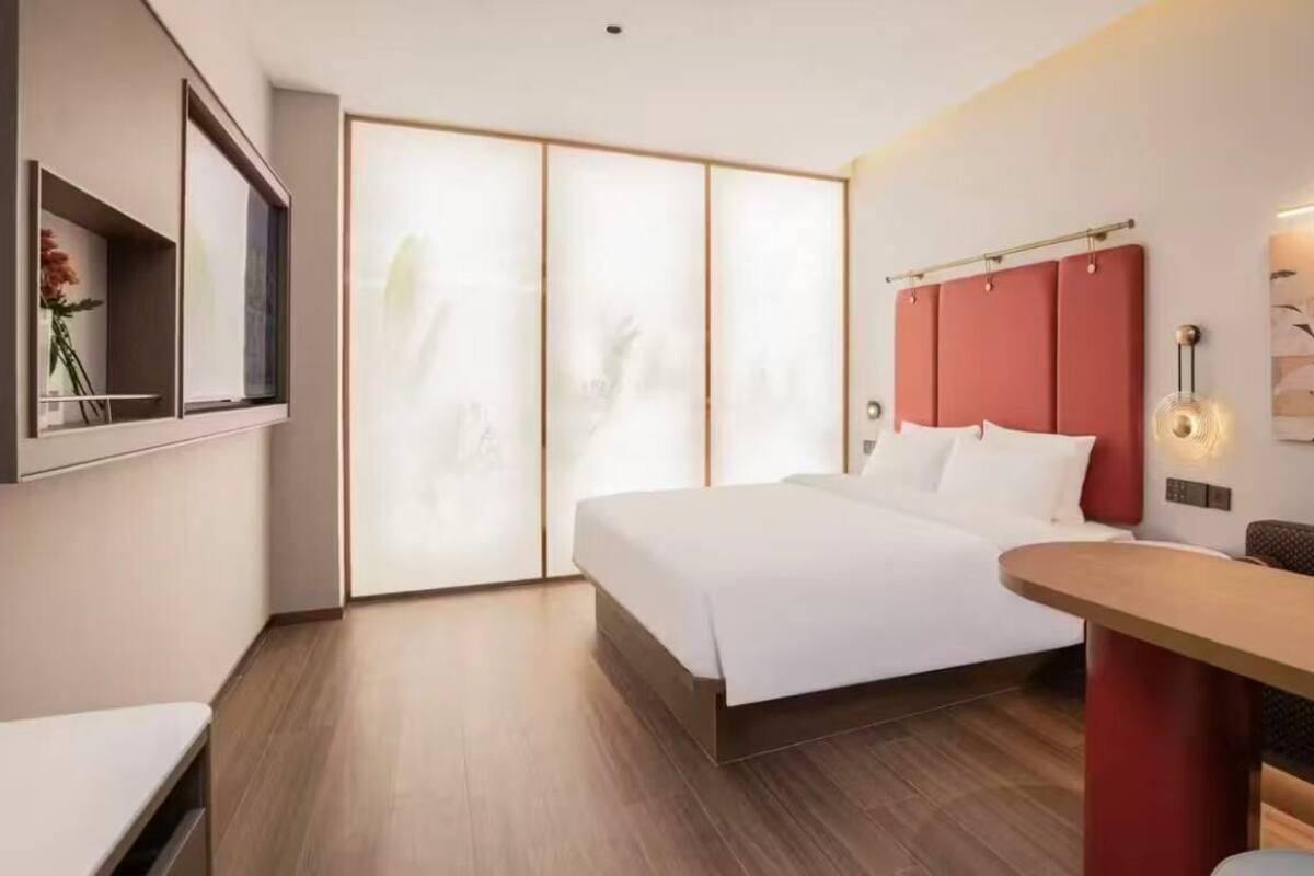 Una habitación de hotel moderna con una cama grande, un escritorio y una puerta corredera que da a un balcón.
