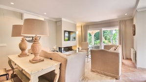 Un salon spacieux doté d’une cheminée, de sièges confortables et offrant une vue sur l’extérieur.