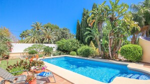 Une piscine avec des chaises longues et des plantes en pot.