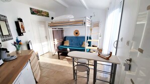 A compact, well-lit room with a bunk bed, a small table with a chair, a TV, and a desk with a computer. - Cosy, fully-equipped Tiny House - private garden (Castanet-Tolosan)