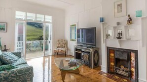 Una sala de estar con una mesa de centro de vidrio, un televisor y una chimenea.