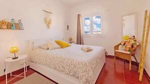 Une chambre à coucher comprenant un lit, une table de chevet, une lampe, des éléments de décoration murale, une fenêtre et une chaise.