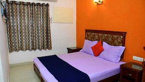 A single-bed room with a wooden headboard, a nightstand, a bedside table, and a curtain. - Sai Nalam Guest Inn (Chennai)