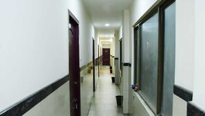A long, narrow hallway with doors on both sides, leading to a central area with a door at the end. - Sai Nalam Guest Inn (Chennai)