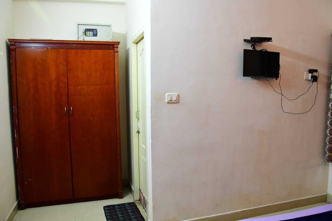 A room with a wooden wardrobe, a wall-mounted telephone, and a power outlet.