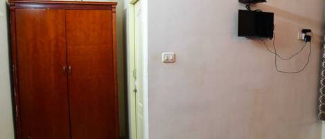 A room with a wooden wardrobe, a wall-mounted telephone, and a power outlet.