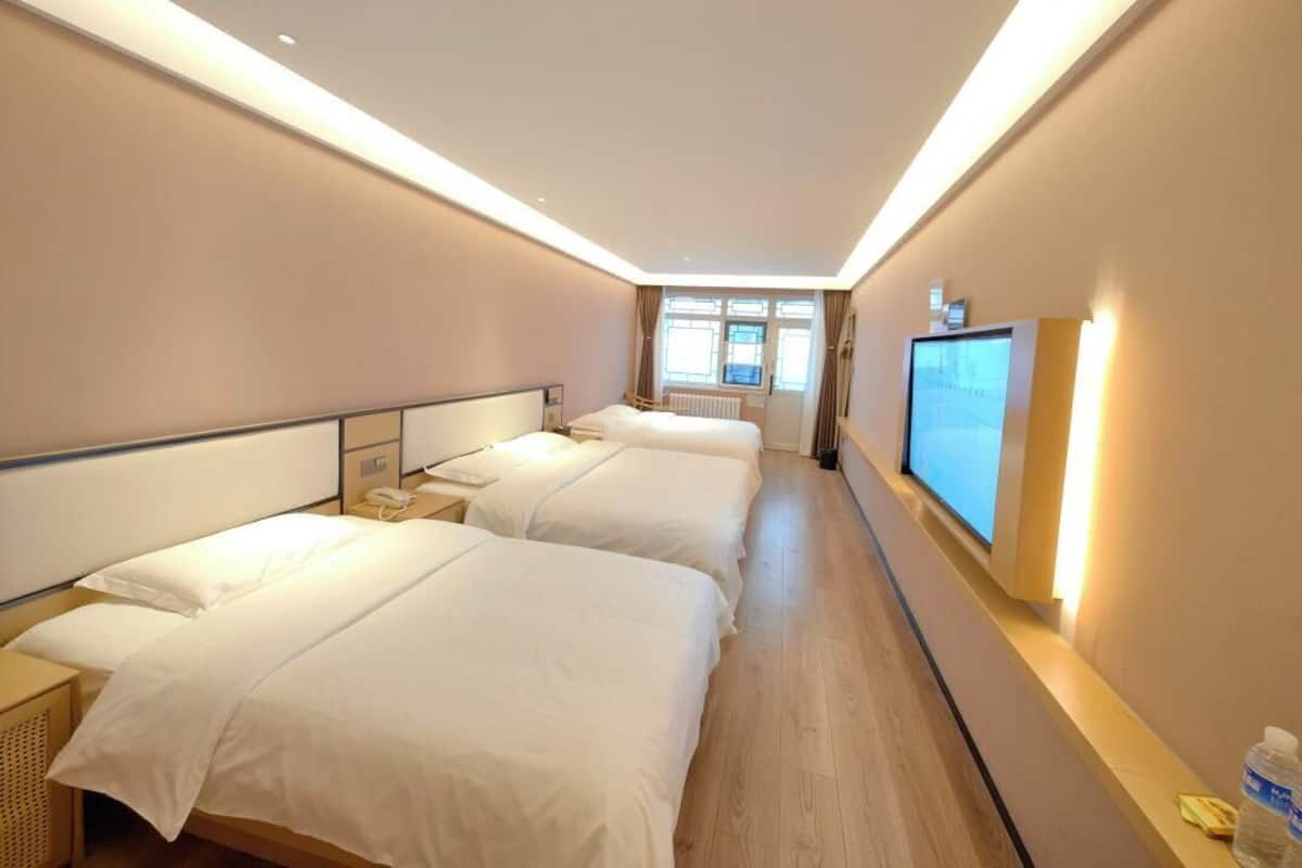 A hotel room with two beds, a television, and a window with curtains.