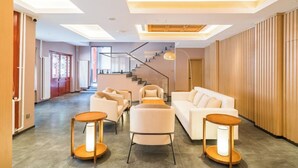 Un hall d’hôtel moderne avec un escalier, un espace salon et un mur en bois.