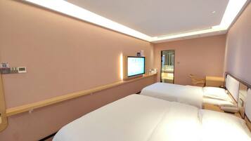 A hotel room with two beds, a television on the wall, and a small desk with a chair.
