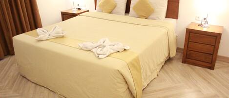 A hotel room with a large bed, two bedside tables, and a wooden headboard.