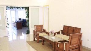 A room with a wooden sofa set, a glass coffee table, and a small vase with flowers. - Salak Boutique Hotel (Bogor)