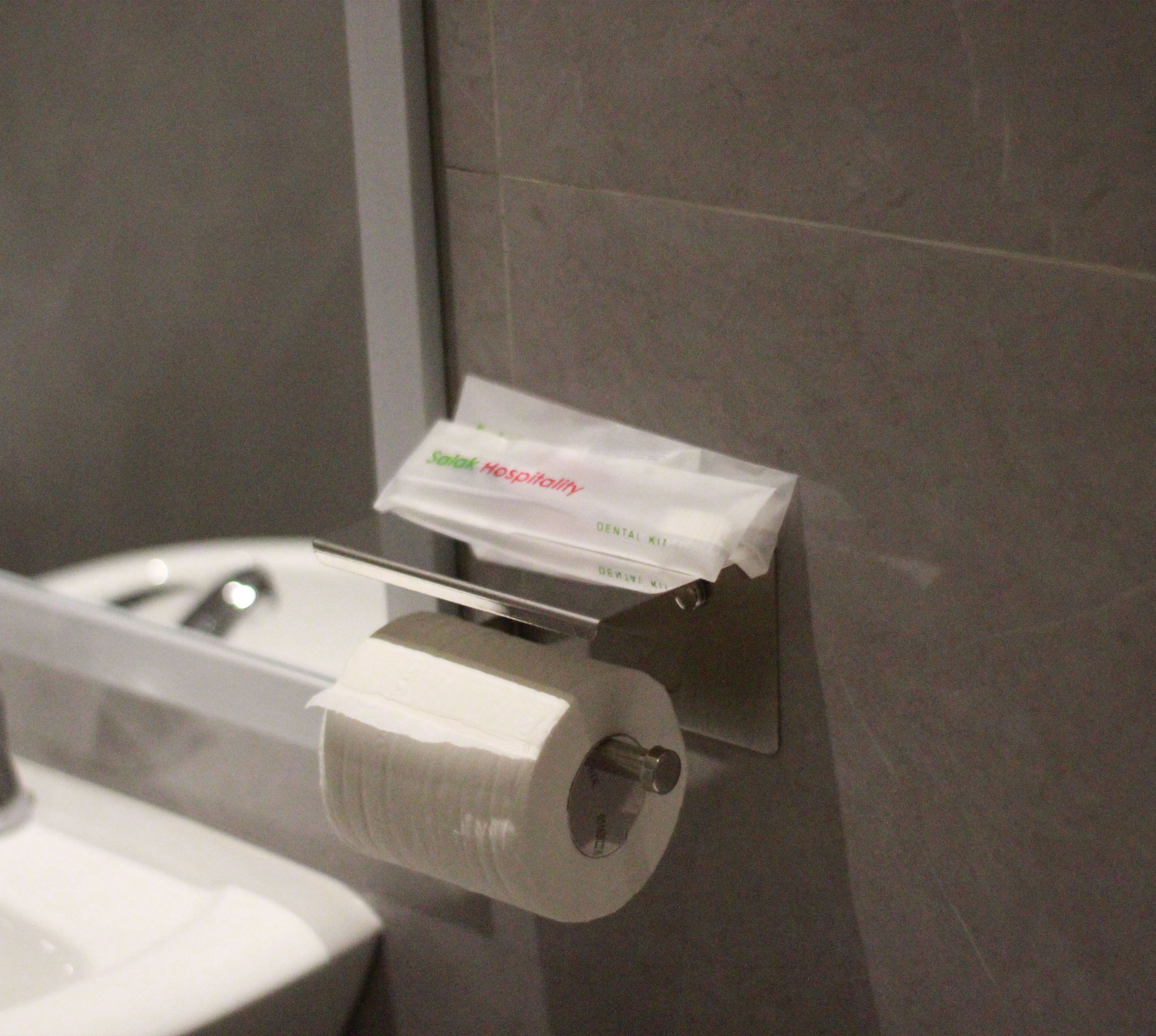 Suporte de papel higiênico com um cartão de marca e um rolo de papel higiênico.
