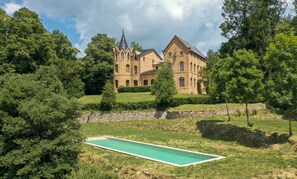 Un edificio de piedra grande con múltiples torres y una piscina al frente.