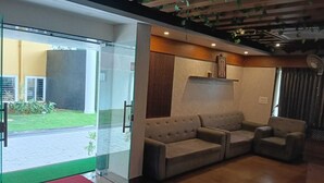 A modern lobby with a glass door leading to a courtyard, a beige sofa, and a red carpet. - RR Residency (Mysore)