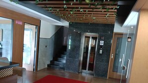 A lobby with a staircase, a reception desk, and a red carpet. - RR Residency (Mysore)