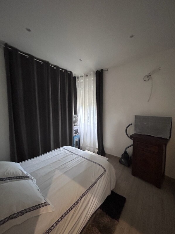 A bedroom with a bed, a small desk, a chair, and a window with curtains. - Newly renovated, comfortable apartment close to all amenities. (Marseille)