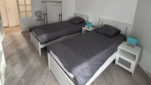 Ein Schlafzimmer mit zwei Betten, einem Kleiderschrank, einem Nachttisch und einer Pendelleuchte.