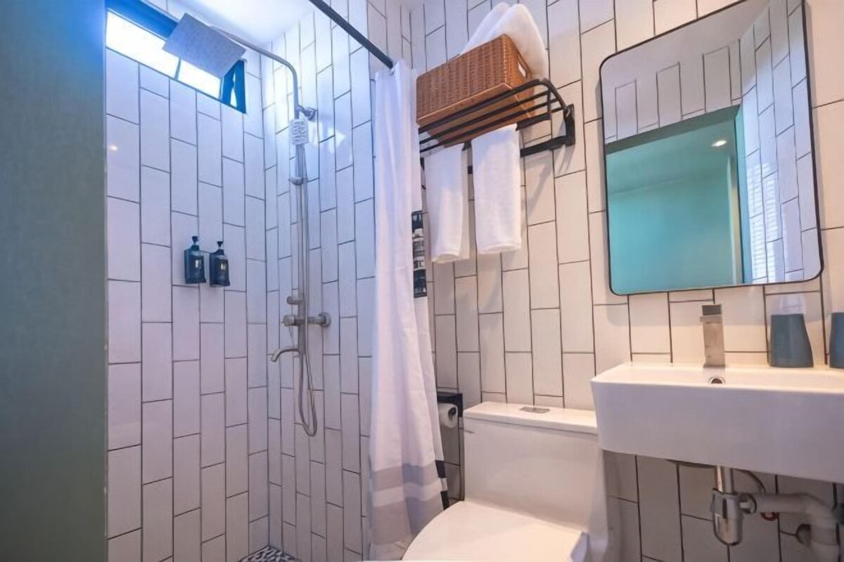 A bathroom with a shower, toilet, sink, and a mirror.