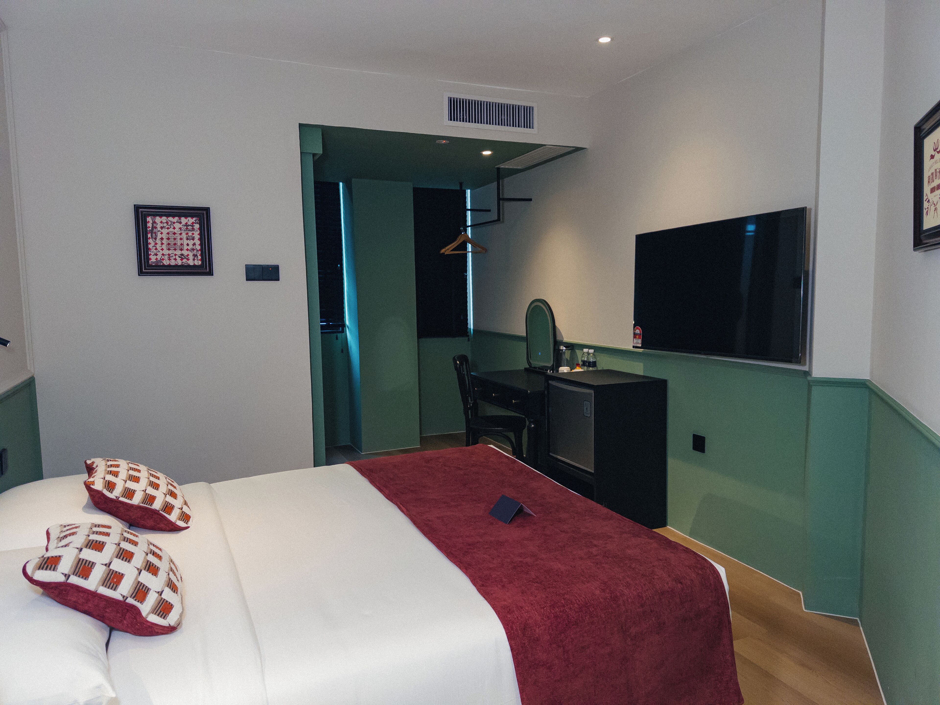 A hotel room with a bed, a desk, a chair, a TV, and a mirror.