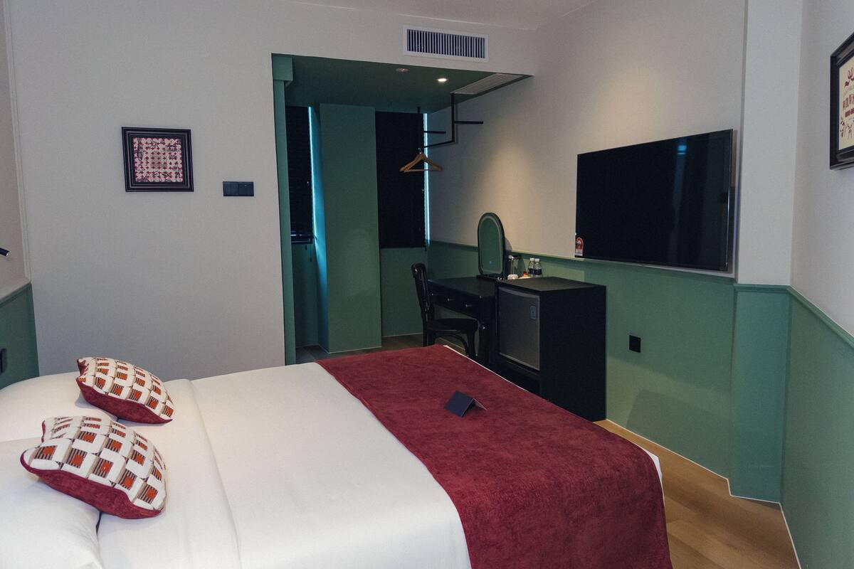 Ein Hotelzimmer mit einem Bett, einem Schreibtisch, einem Stuhl, einem Fernseher und einem Spiegel.