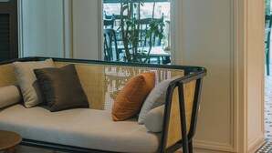A modern living room with a sofa, a large potted plant, and a patterned rug. - Legacy Hill Hotel (Kuching)
