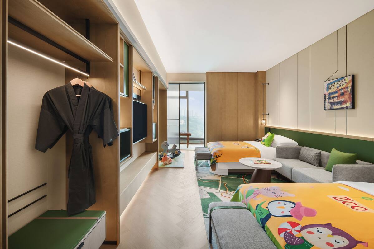 Habitación de hotel con cama, sofá, televisor, armario y ventana con vistas.