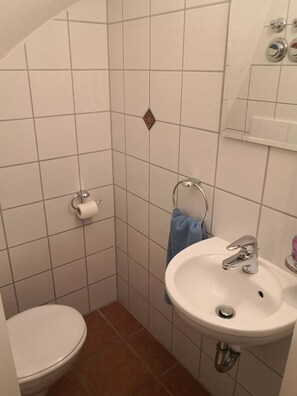 A small bathroom with a toilet, sink, and towel rack.