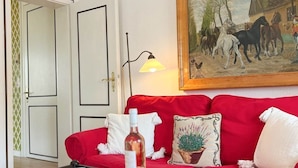 A red sofa with a painting of horses, a lamp, and a bottle on a table. - House Friesland - Apartment 1 - An urban villa with spacious and tasteful (Sylt)