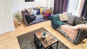 Un salon moderne avec un canapé gris, une table basse en bois et un fauteuil noir.