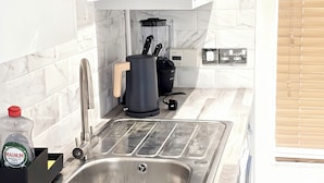 Une cuisine moderne équipée d’un évier en acier inoxydable, d’une machine à café et d’une bouteille de détergent Magnum.