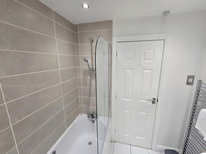 Huis | Badkamer | Een bad/douchecombinatie, een diep bad, een haardroger, handdoeken