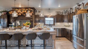 A modern kitchen with a central island, stainless steel appliances, and decorative elements. - Hot Tub, Firepit & Views, Sleeps 19 | Winterhaven Estate by AvantStay (Winter Park)