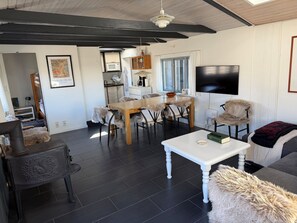 A modern living room with a wooden dining table, a white coffee table, and a sofa with fur throw. - Lovely cottage near beautiful bathing beach (Otterup)