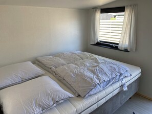 A single bed with a mattress, pillows, and a window with blinds.