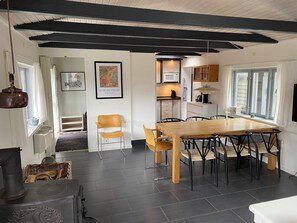 Een moderne keuken met een eethoek, met een houten tafel en stoelen, een fornuis en een foto in een lijst aan de muur.