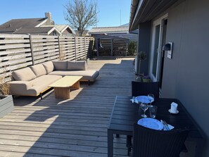 Une terrasse en bois avec un canapé, une table et une chaise.