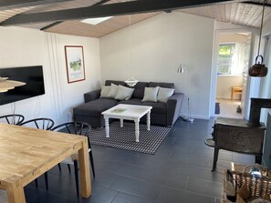 Ein modernes Wohnzimmer mit einer Couch, einem Esstisch und einem an der Wand befestigten Fernseher.