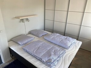 Un lit avec une tête de lit, des oreillers et une table de chevet avec des lampes.