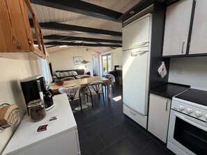 Een moderne keuken met een eethoek, houten balken in het plafond en een koelkast.