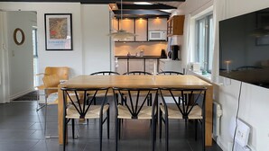 Una cocina moderna con comedor, que incluye una mesa y sillas de madera, una obra de arte enmarcada y un amplio ventanal.