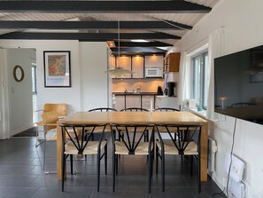 Une cuisine moderne avec un coin repas, comprenant une table et des chaises en bois, une œuvre d’art encadrée et une grande fenêtre.