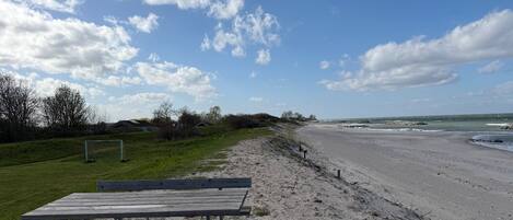 Une plage avec un banc en bois, un but de football et une côte rocheuse.